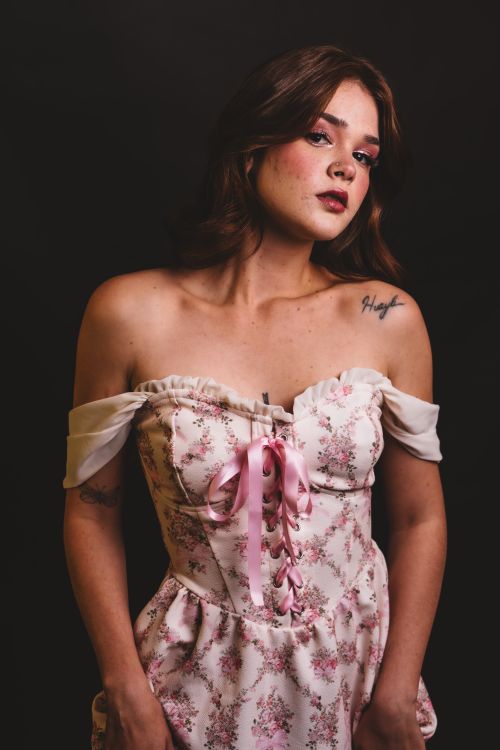 Free Elegant portrait of a woman in a floral off-shoulder dress with a dark studio background. Stock Photo