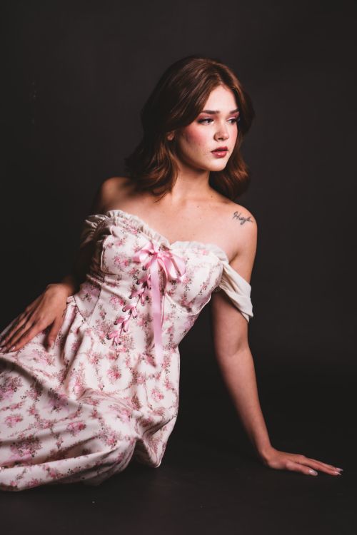 Free A poised woman in a floral off-shoulder dress poses gracefully against a dark backdrop. Stock Photo