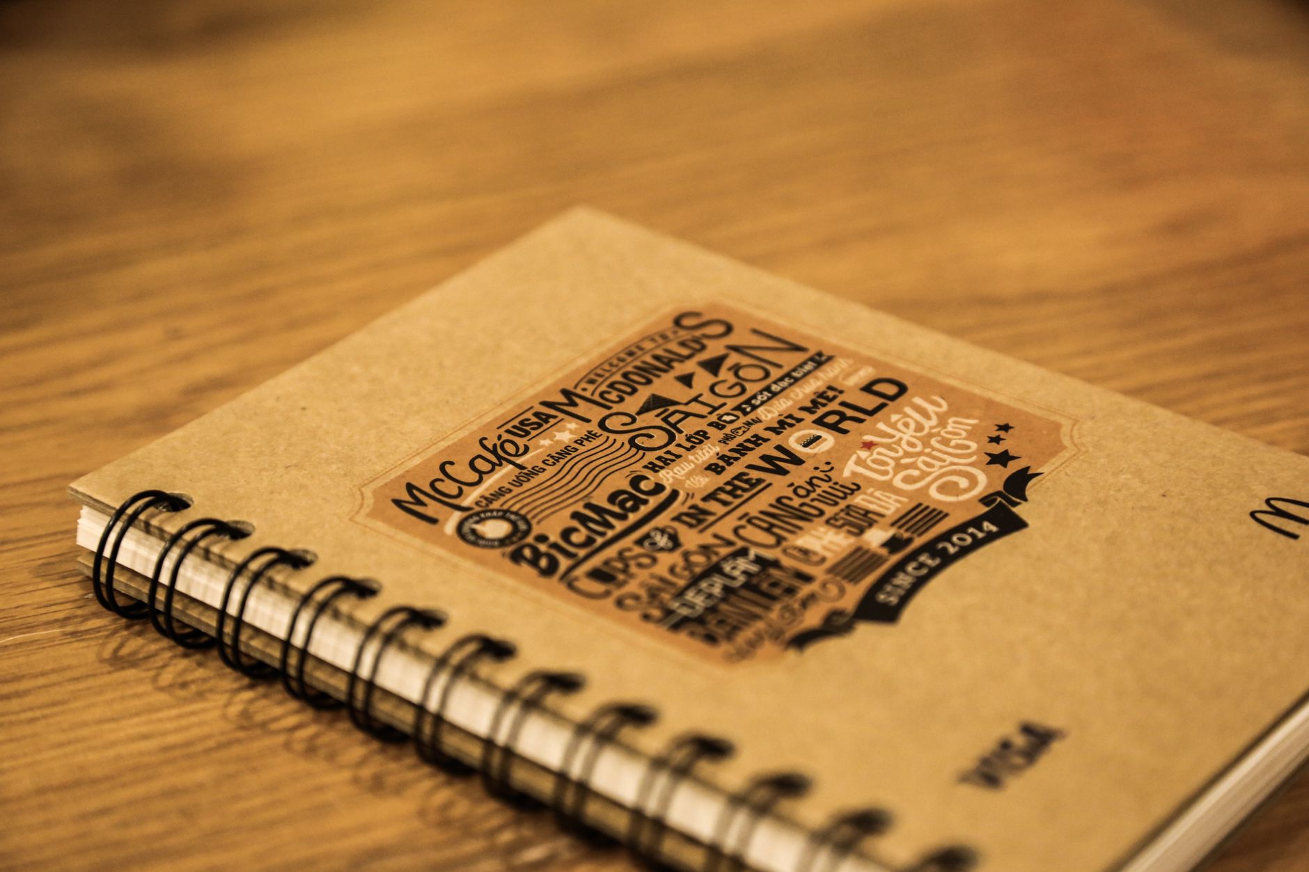Rustic spiral notebook with unique typography design on a wooden table.