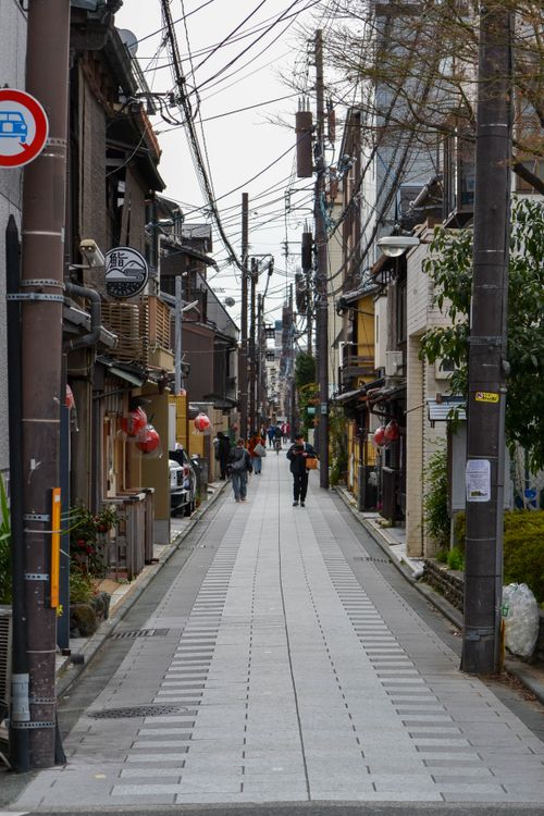Free Narrow alleyway in Kyoto featuring traditional architecture, power lines, and a few pedestrians. Stock Photo
