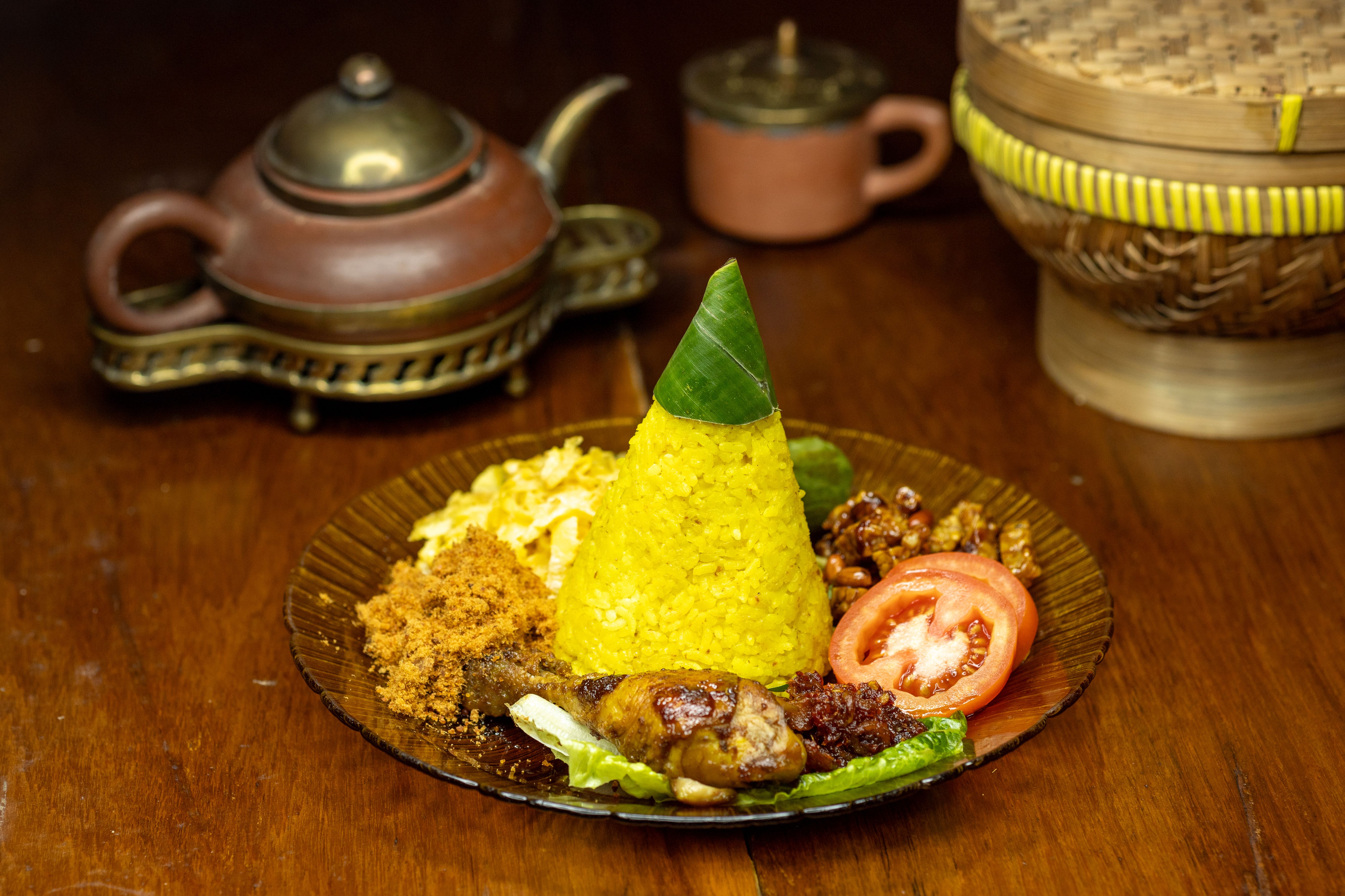 Plate of Nasi Tumpeng, an Indonesian cone-shaped rice dish with various sides, served indoors.