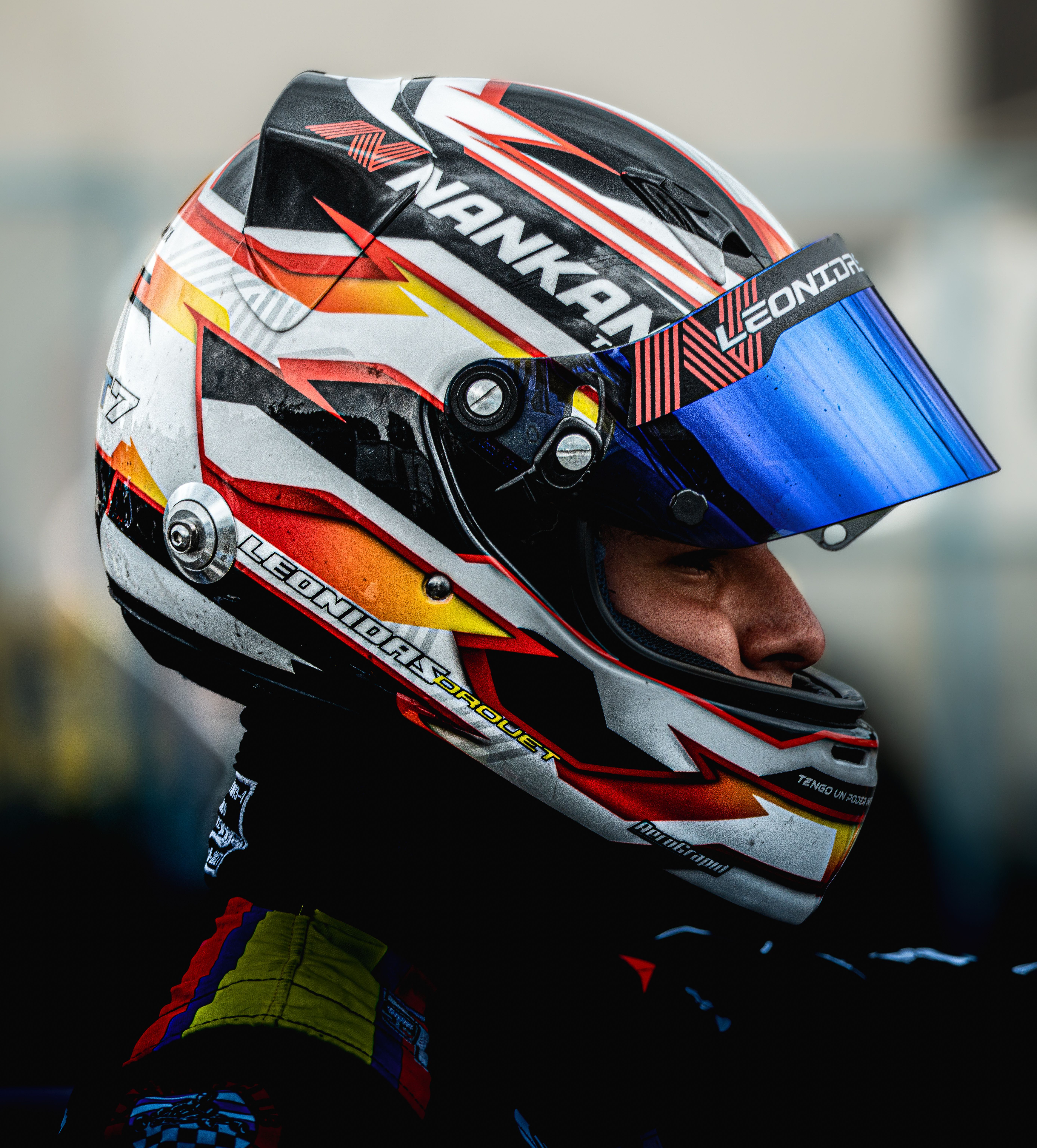 Close-up of a race car driver wearing a vibrant, colorful helmet, preparing for a race.