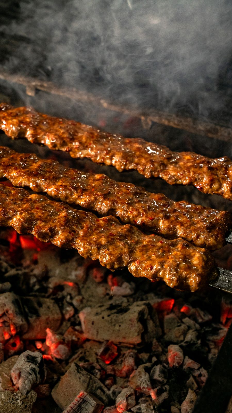 Seekh kebabs on skewers over glowing charcoal