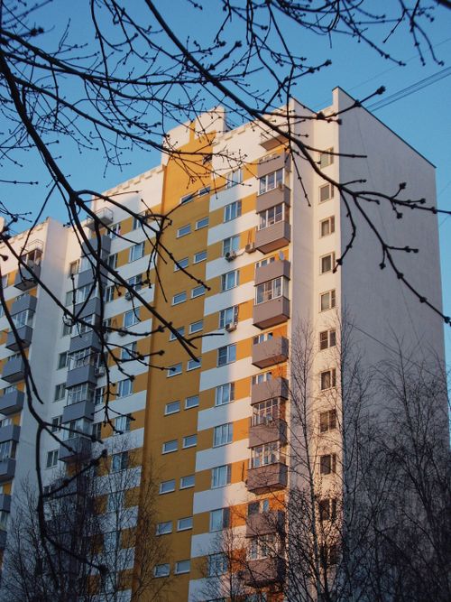Free A modern high-rise apartment building set against a clear blue sky during sunset. Stock Photo