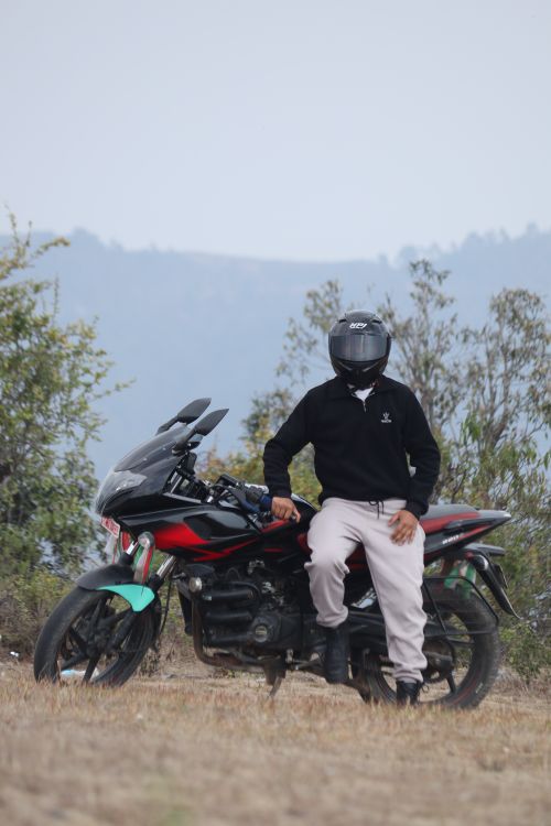 Free A motorcyclist wearing a helmet seated on a red and black motorcycle in a natural setting. Stock Photo
