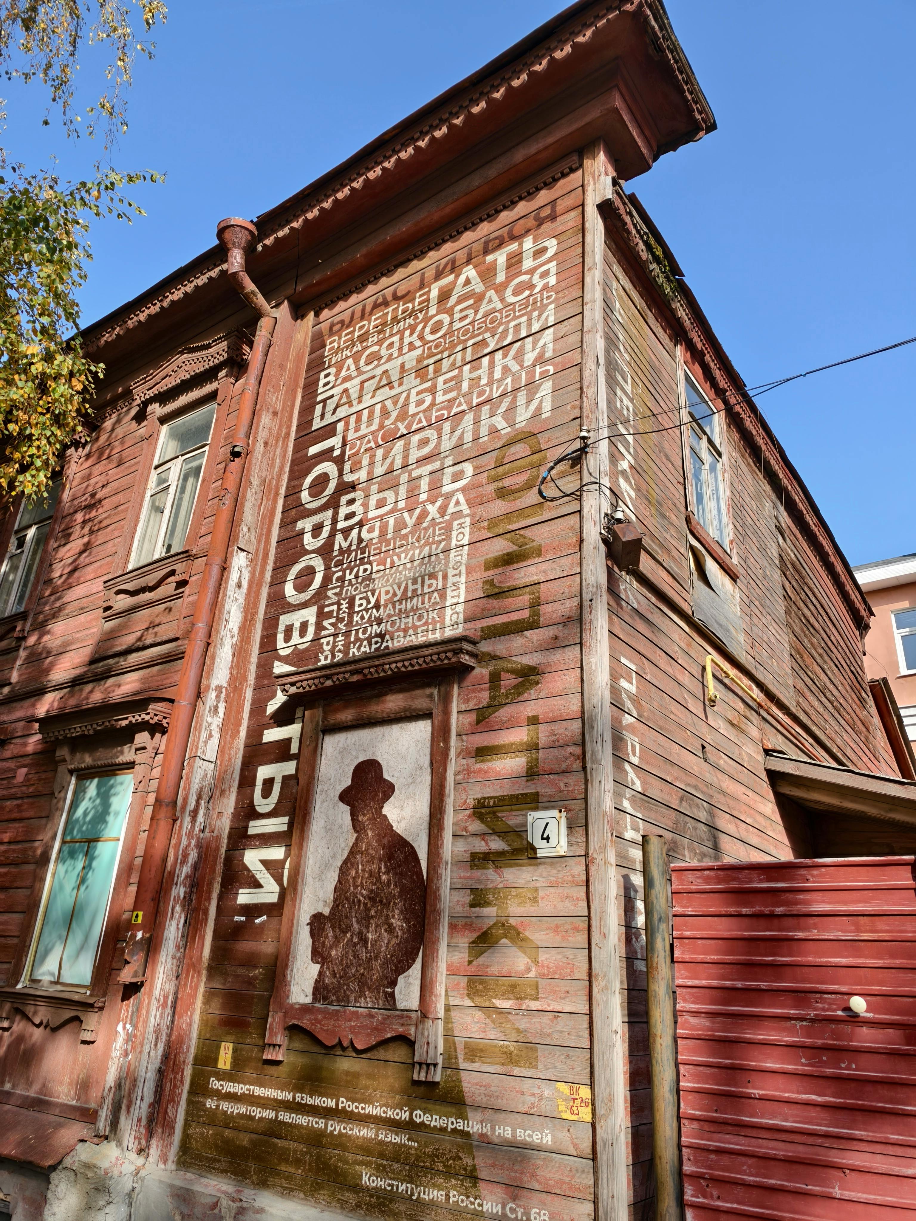 De franc Una foto d'una casa rústica de fusta amb tipografia russa i art mural en un dia assolellat. Foto d'estoc