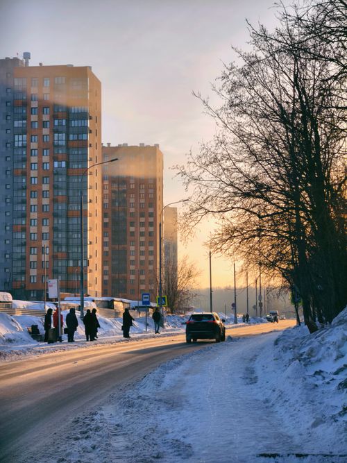 Free Sunrise over snowy urban street with high-rise buildings and morning traffic in winter. Stock Photo