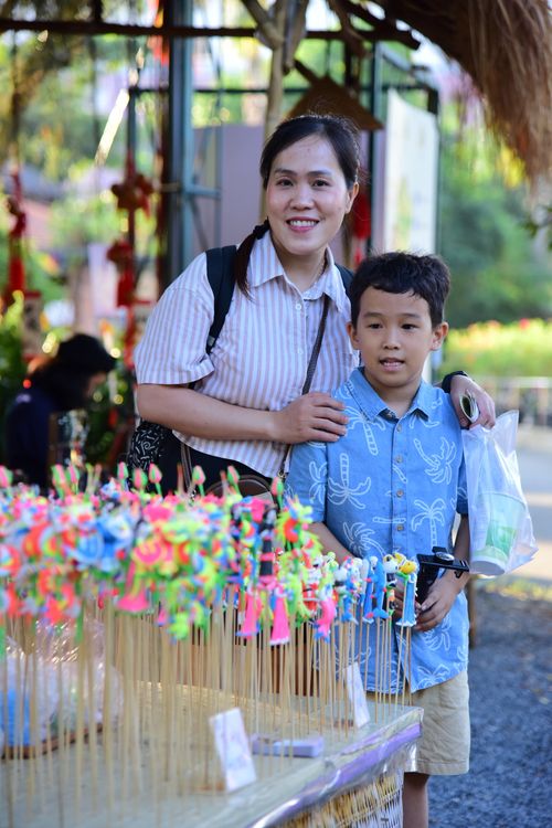 Free A mother and son smile while browsing colorful toys at an outdoor market. Stock Photo