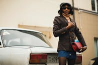 一位穿着时髦的时尚女性，在户外一辆经典汽车旁自信地摆着姿势