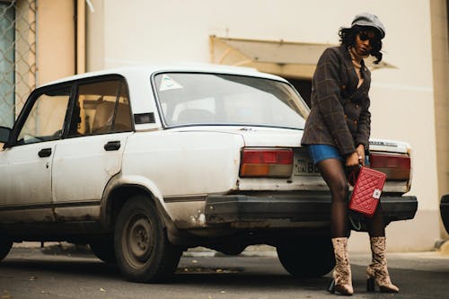 Femme chic posant près d’une voiture rétro