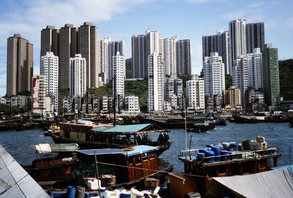 香港の港に浮かぶ色とりどりのボートと、その背景にそびえ立つ近代的な超高層ビル群。