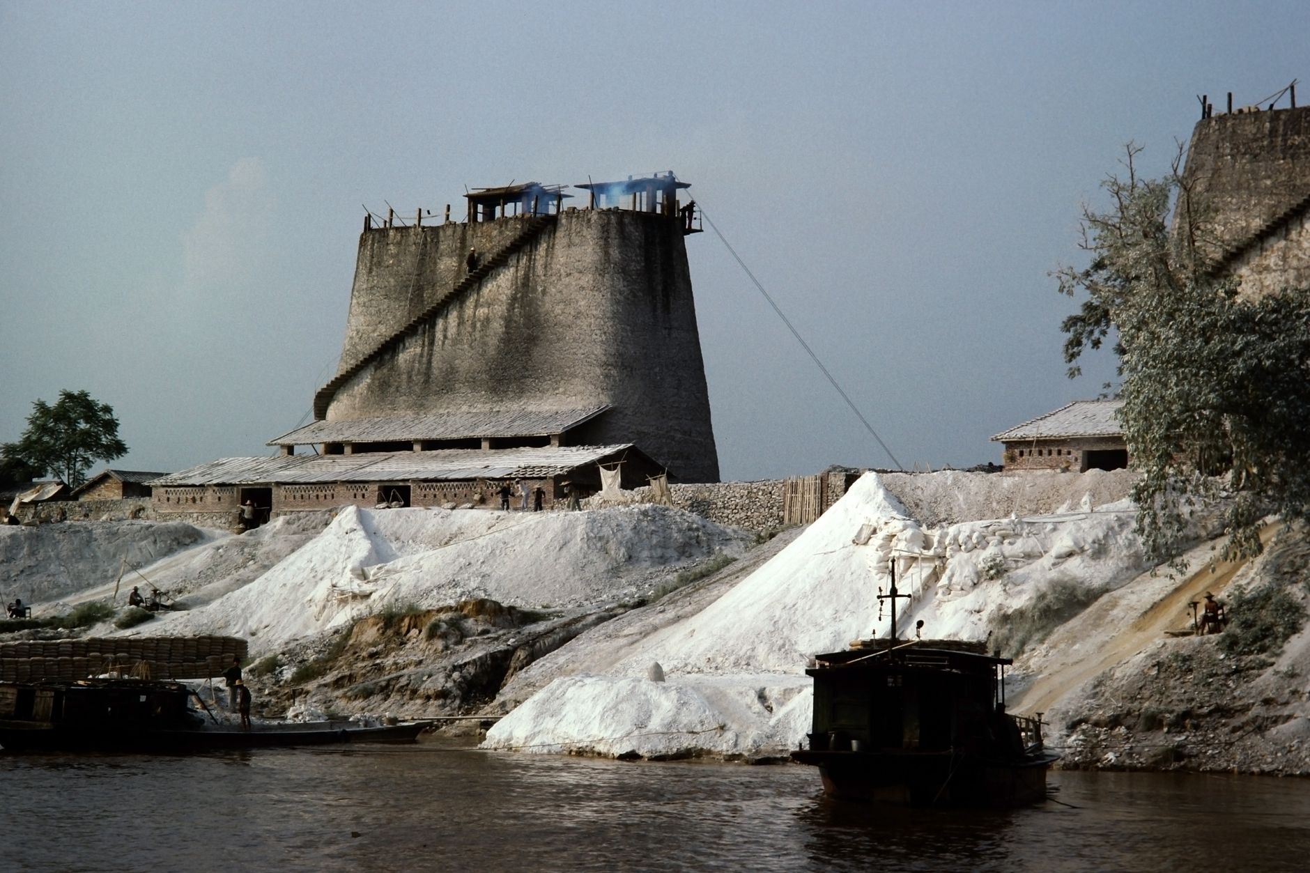 A scenic view of a traditional salt production site in rural China with old structures by a river.