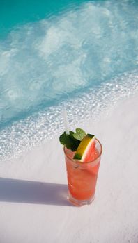 Chilled watermelon cocktail with mint garnish by a sunlit swimming pool.