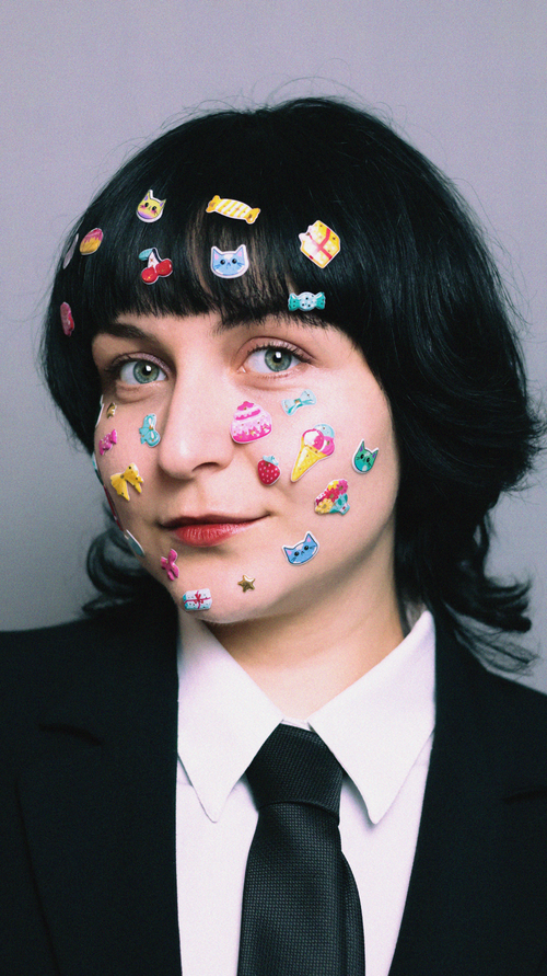Free Woman in a black suit with colorful stickers on her face, whimsical expression. Stock Photo