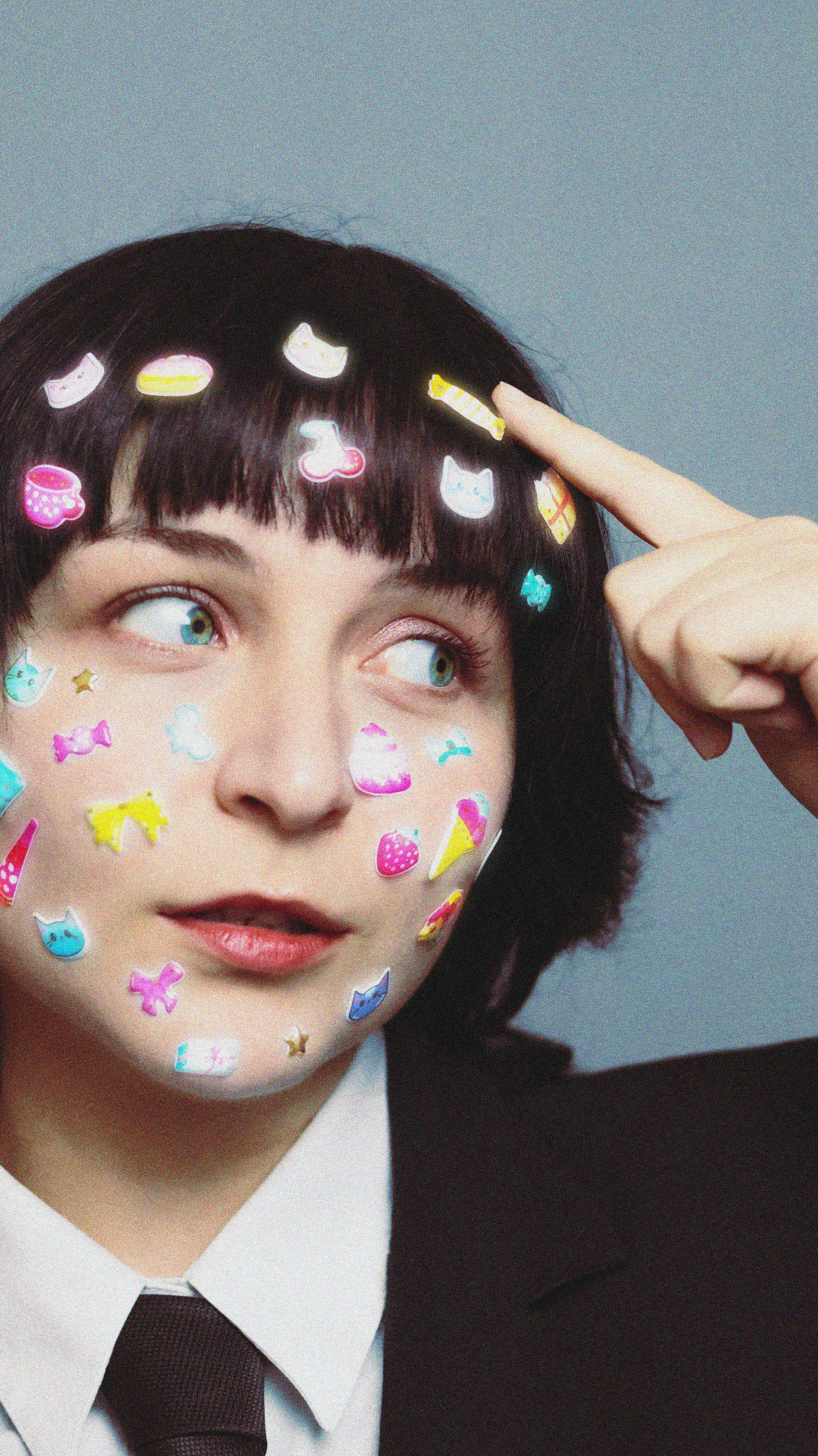 Woman with colorful stickers on face, expressing whimsical creativity.