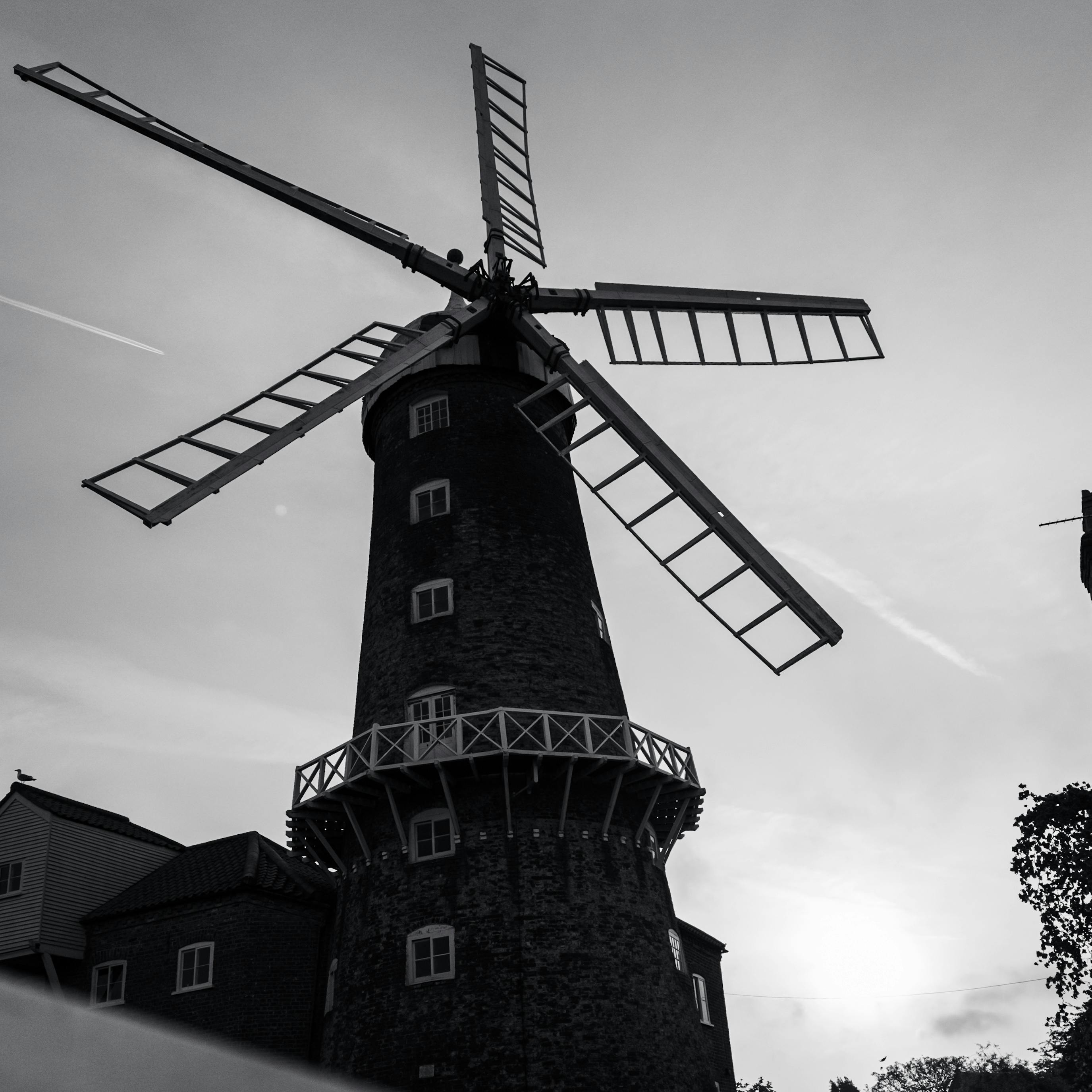 A striking black and white silhouette of a historic windmill in the United Kingdom during sunset.