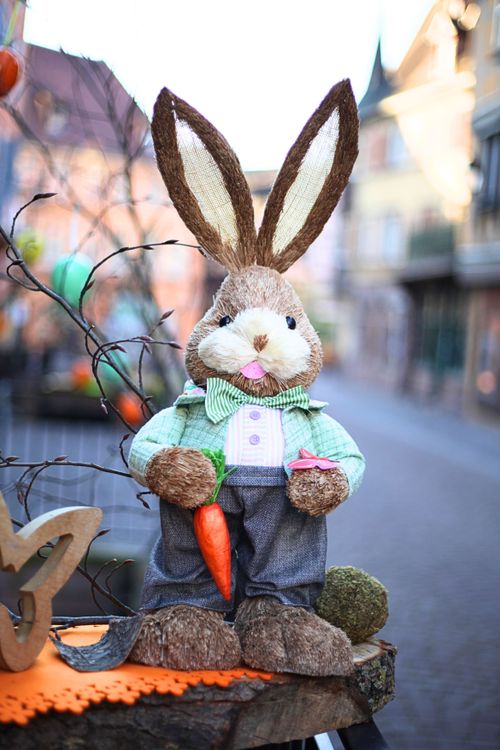 Free Adorable Easter bunny decoration holding a carrot on a city street. Stock Photo