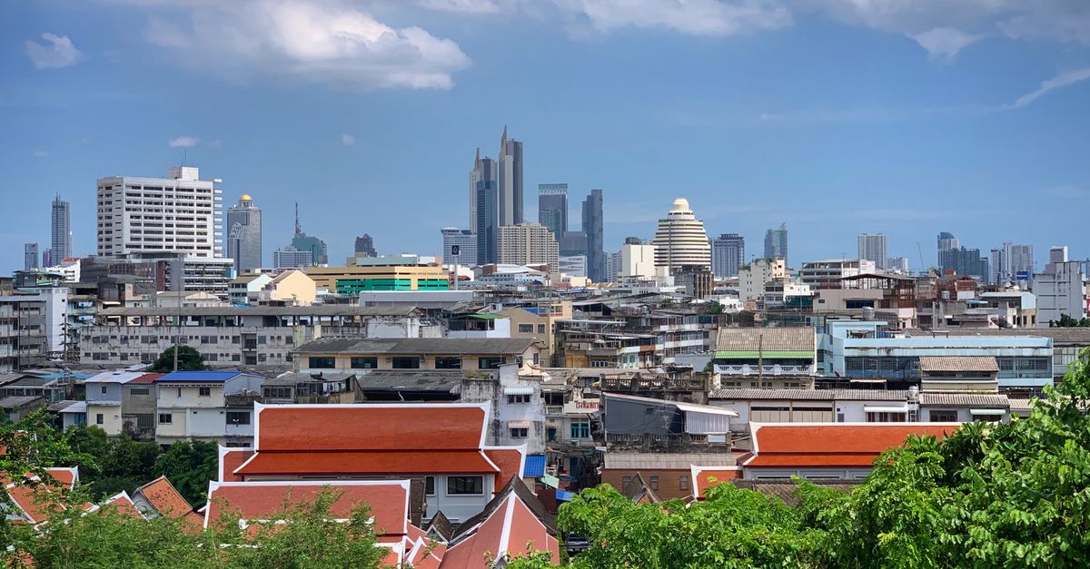 Stunning view of Bangkok's modern skyline juxtaposed with traditional Thai rooftops below.