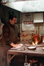 Side view concentrated ethnic craftsman in dirty casual wear burning copper ware in fire in messy workshop