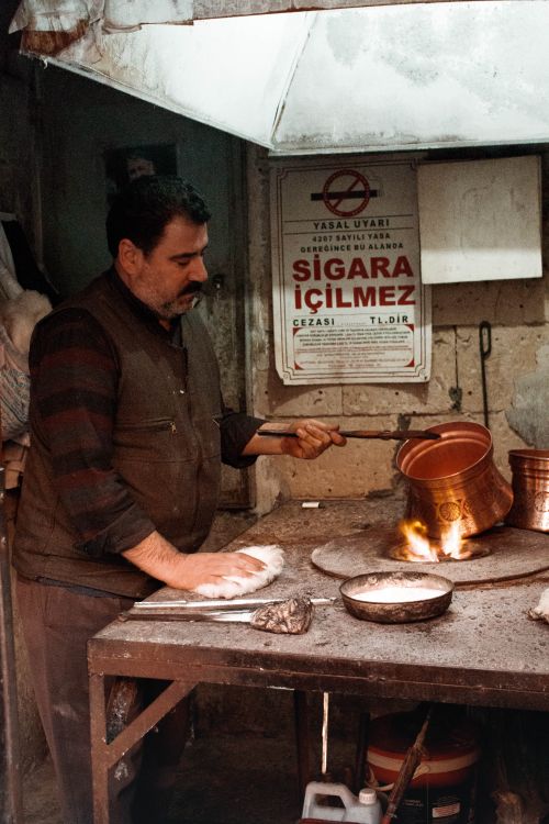 Free Side view concentrated ethnic craftsman in dirty casual wear burning copper ware in fire in messy workshop Stock Photo