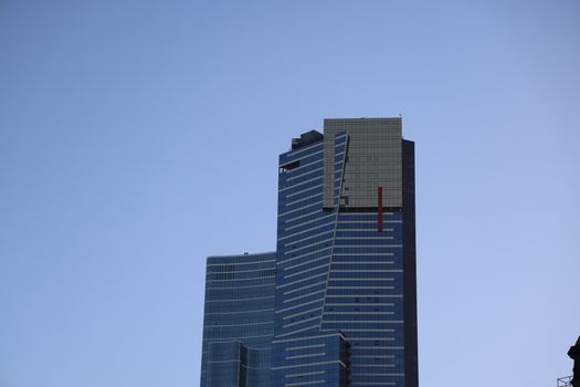 Tall modern skyscraper with unique design against a clear blue sky.
