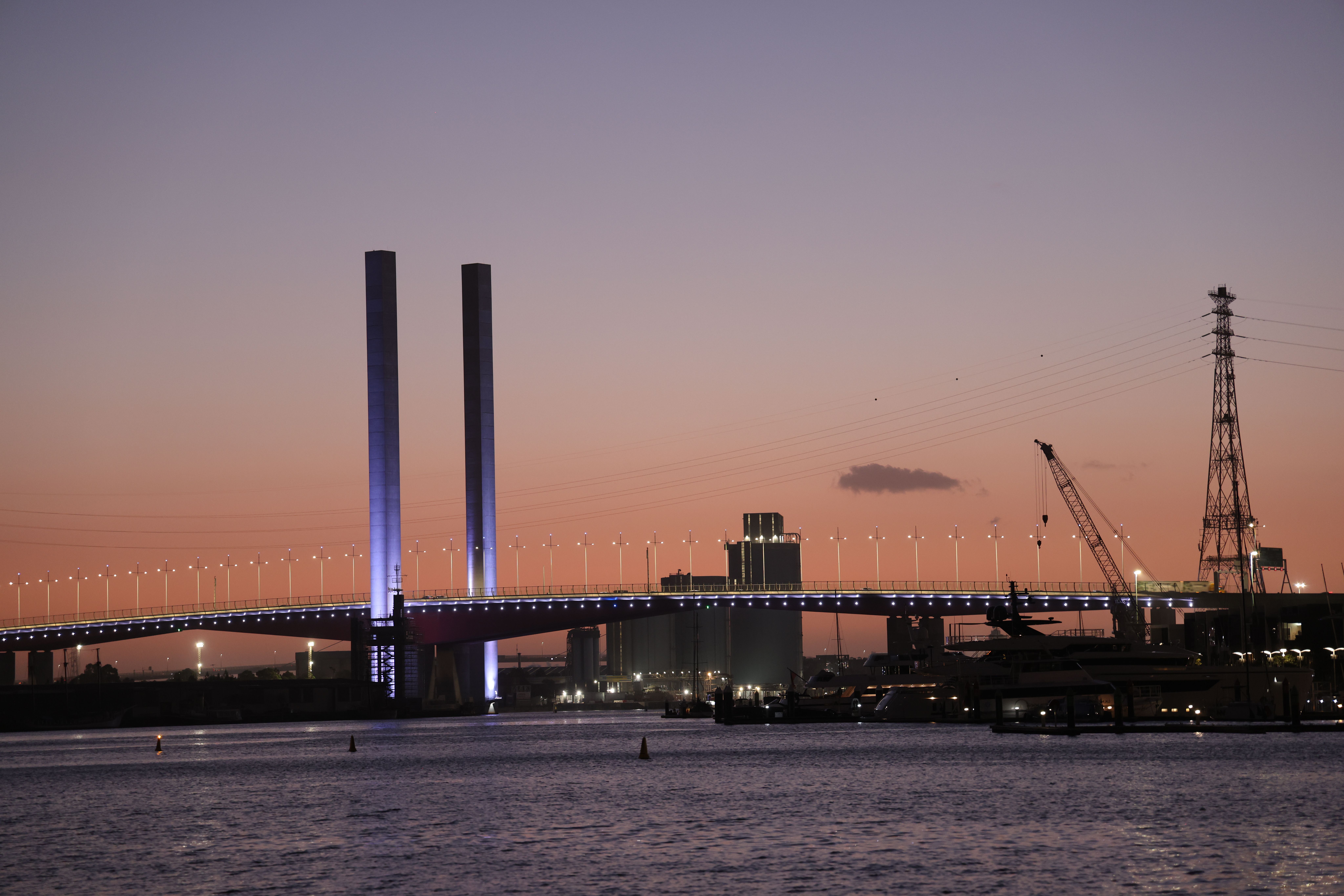 A stunning view of Bolte Bridge silhouetted against a colorful sunset in Melbourne harbor, Australia.