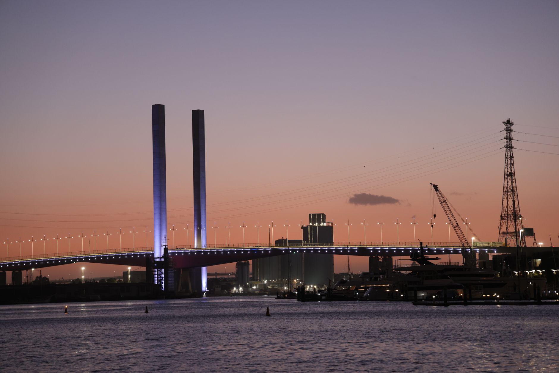 A stunning view of Bolte Bridge silhouetted against a colorful sunset in Melbourne harbor, Australia.