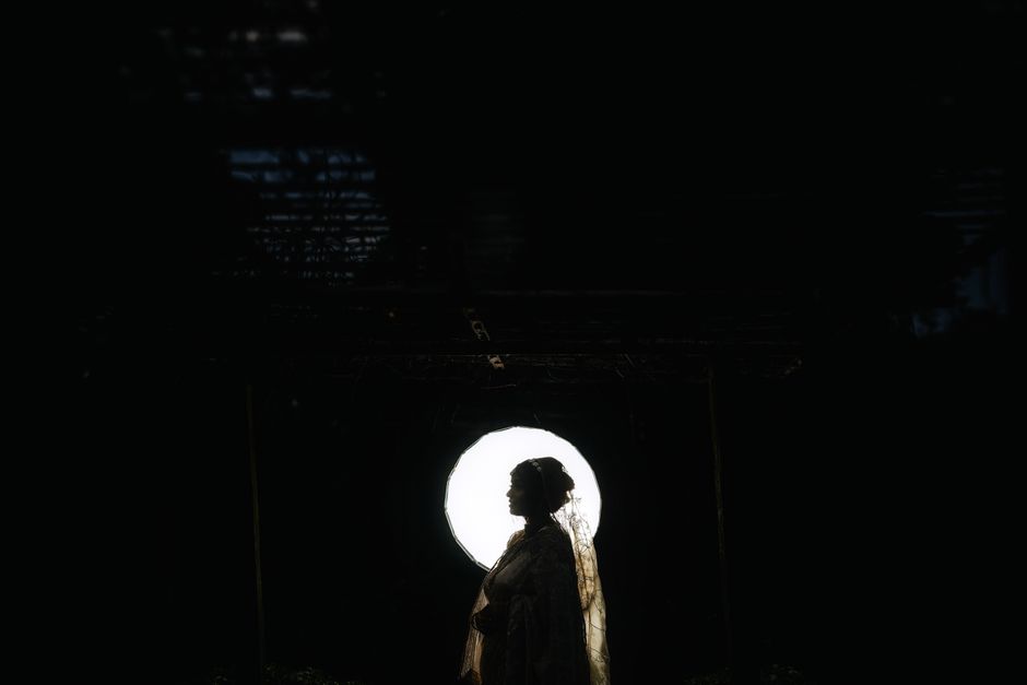 Dramatic silhouette of a person against a bright circular backdrop, emphasizing mystery and contrast.