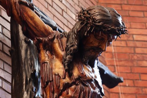 Free A close-up view of a wooden crucifix depicting Jesus Christ with a crown of thorns inside a historic church. Stock Photo