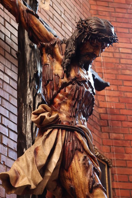 Free Detailed wooden sculpture of Christ crucified against a brick wall in El Puerto de Santa María, Spain. Stock Photo