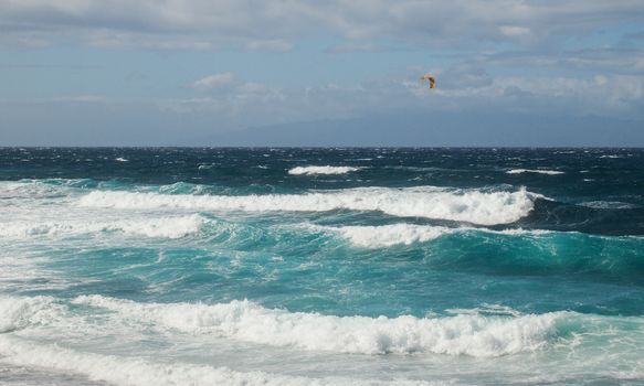 Vibrant ocean waves with a kite surfer in the distance, capturing the essence of sea adventure.