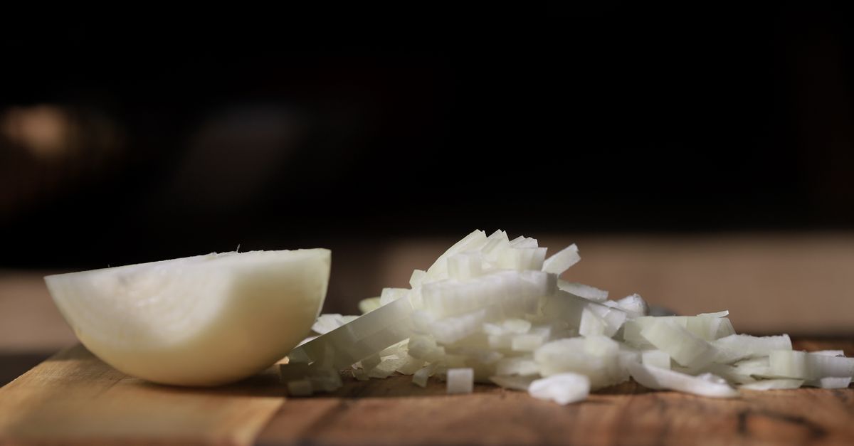 Will a Small Amount of Onion Hurt My Dog Small amount of onion risk for dogs: diced white onion and a cut onion half on a wooden cutting board