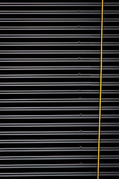 波纹金属面板的特写展示了其条纹纹理和工业设计，并配有一条醒目的黄色电缆