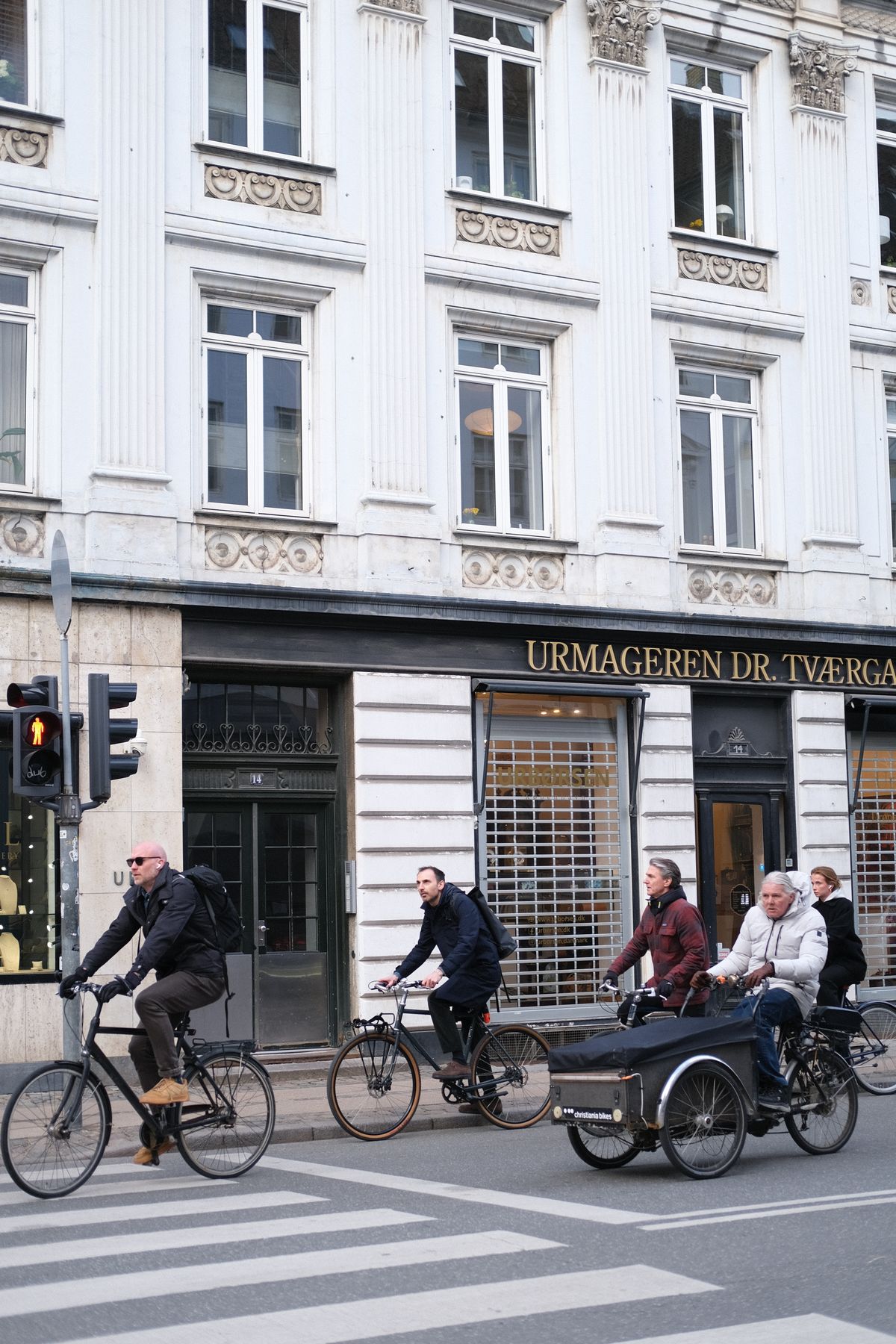 Unde te cazezi în Copenhaga - bicicliști trecând pe lângă clădiri istorice