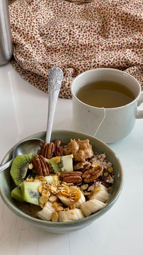 Free A nutritious breakfast with granola, kiwi, nuts, and a cup of green tea, set on a cozy cloth background. Stock Photo