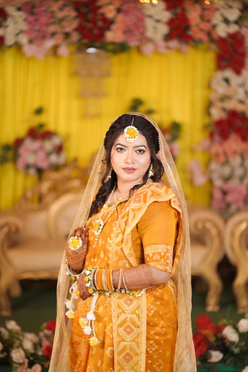 Free Stunning portrait of a bride in traditional Indian attire with floral backdrop. Stock Photo