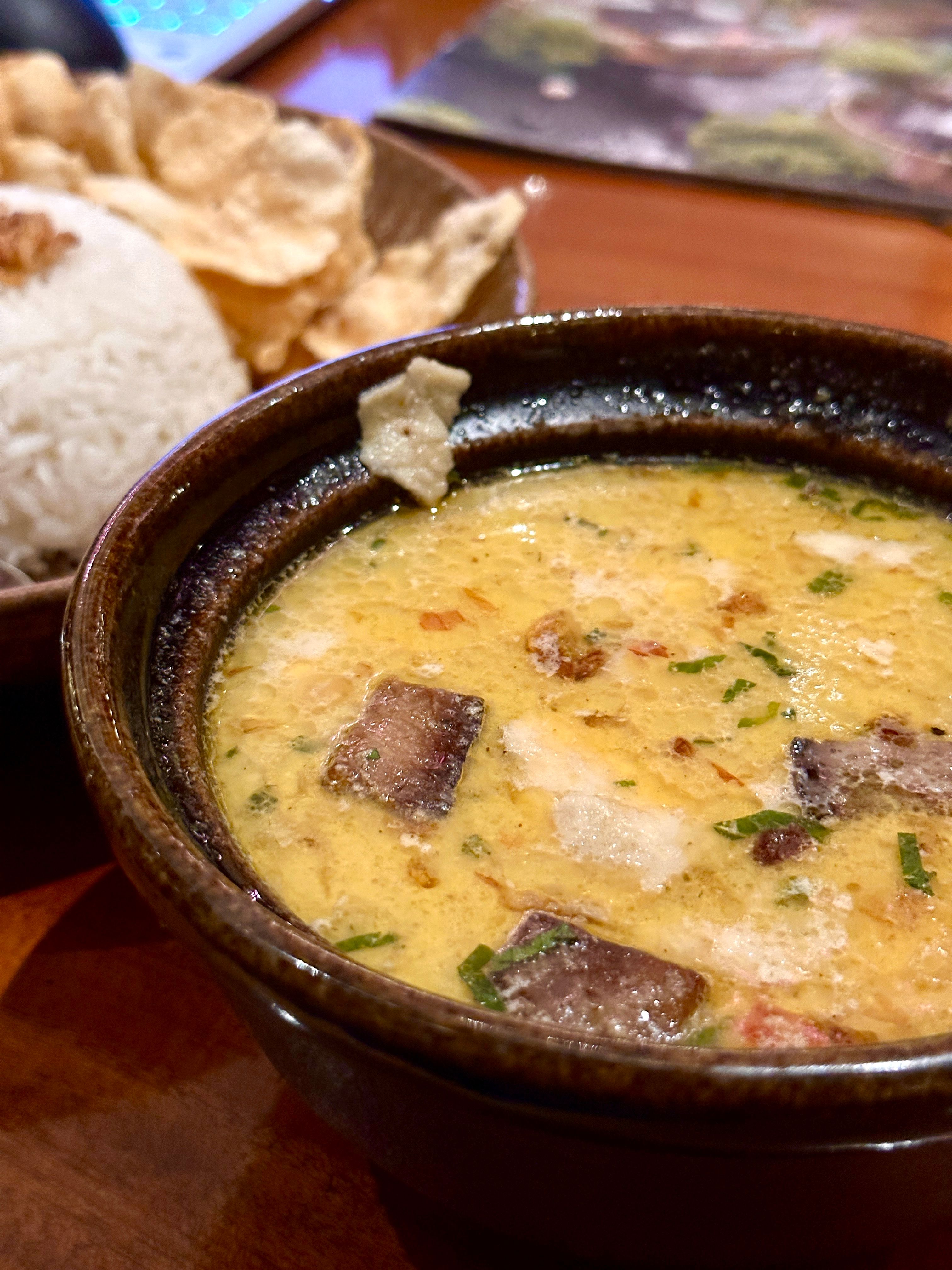 A bowl of bicol express showing creamy coconut sauce with visible red siling labuyo chilies and tender pork