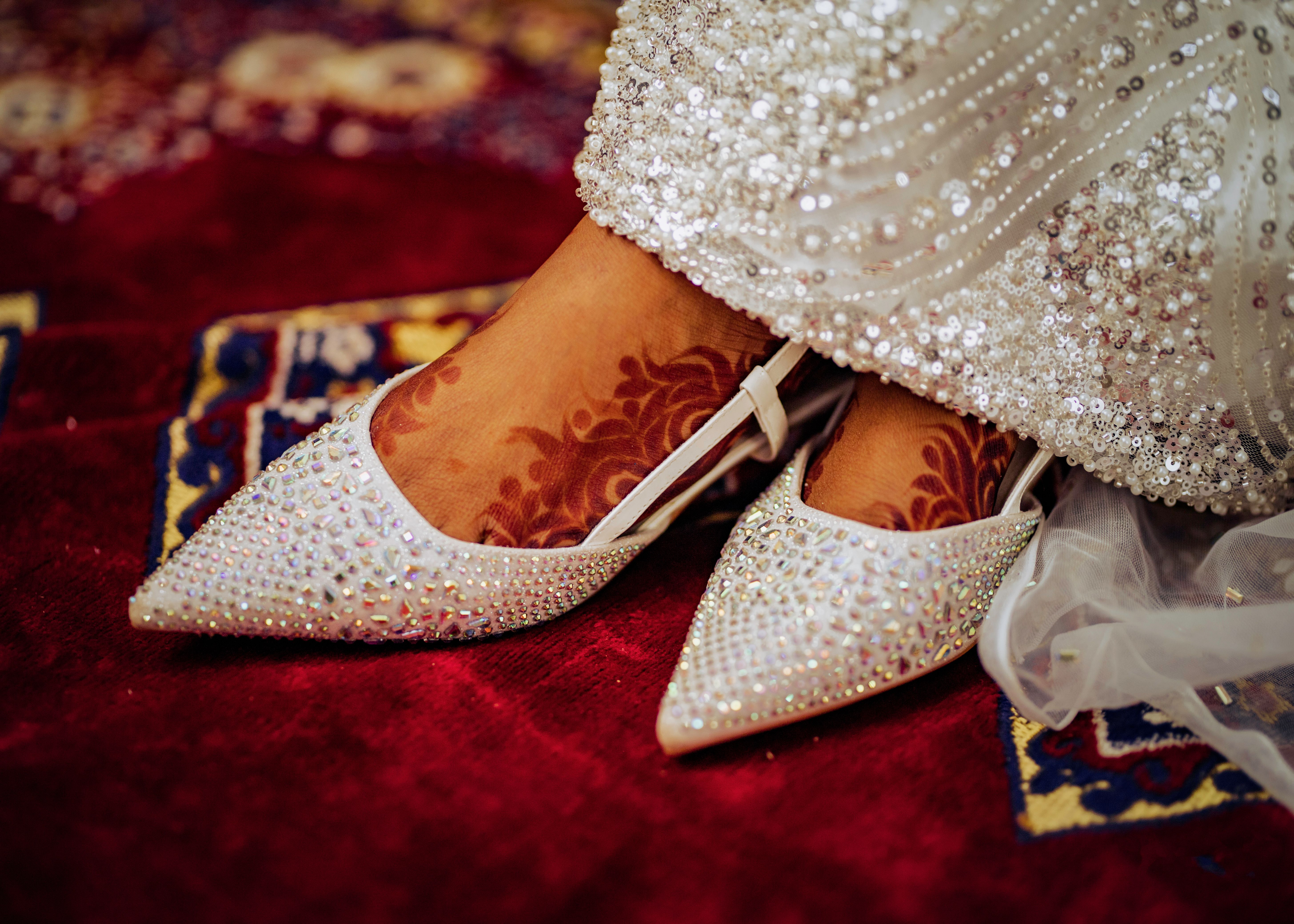 Close-up of bridal shoes adorned with henna design, captured on a traditional red carpet in Kano, Nigeria.