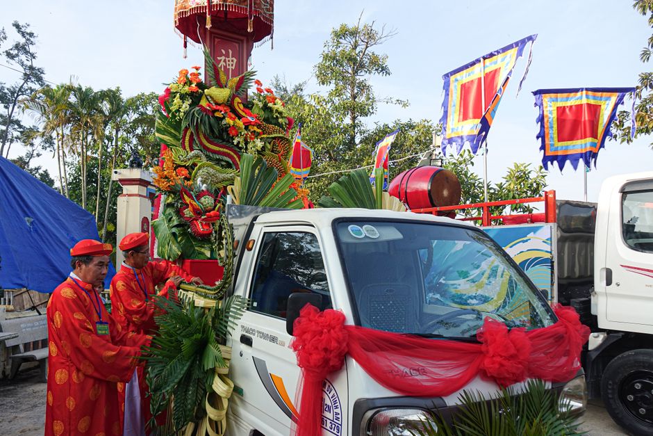 Colorful festival with traditional attire and decorated vehicle outdoors.