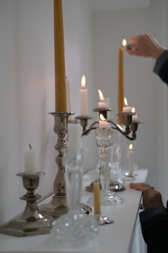 Tapers and pillar candles being lit on a mantel — photo by Burcu Elmas on Pexels
