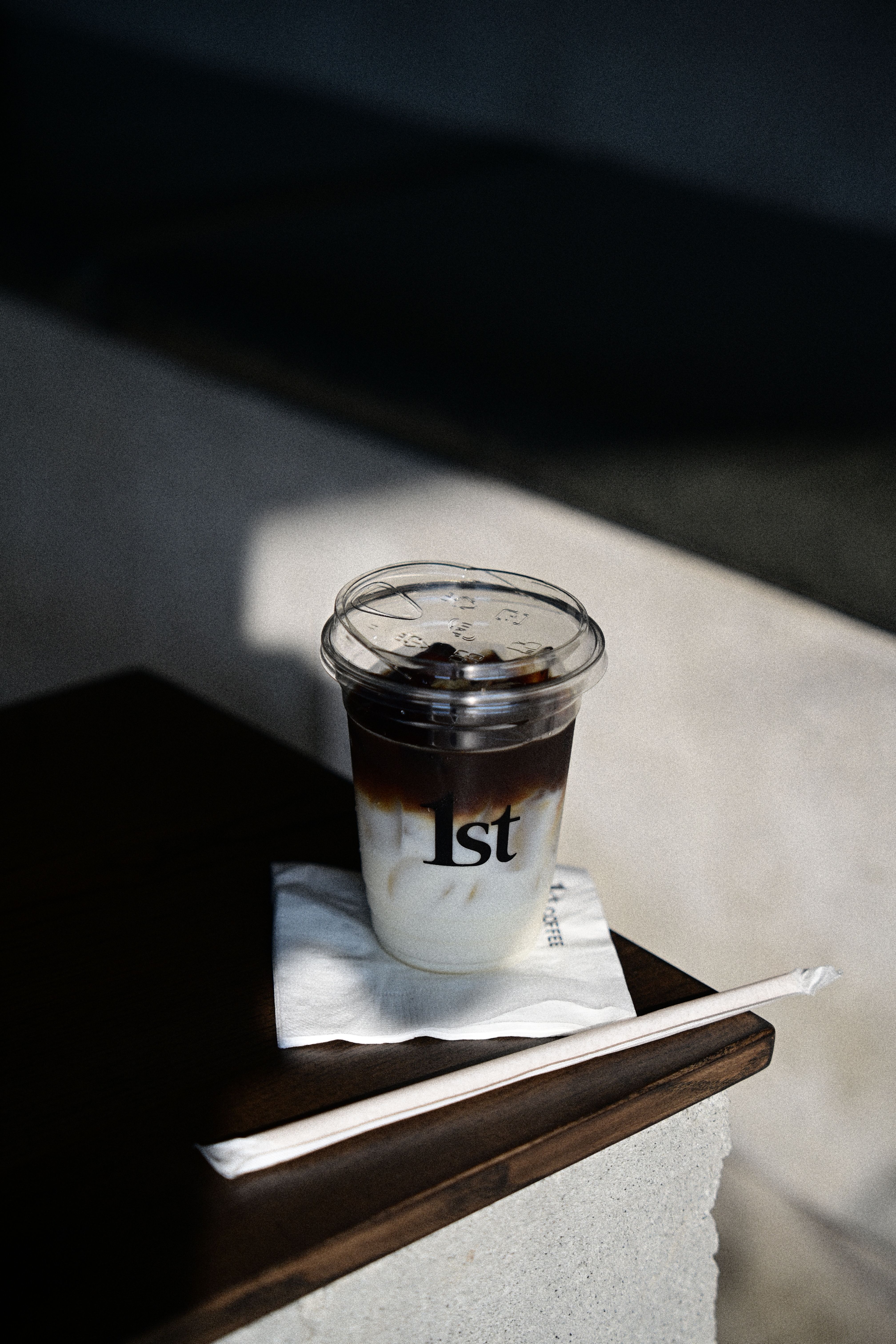 Elegant shot of iced coffee in sunlight on a wooden table, minimalist style.