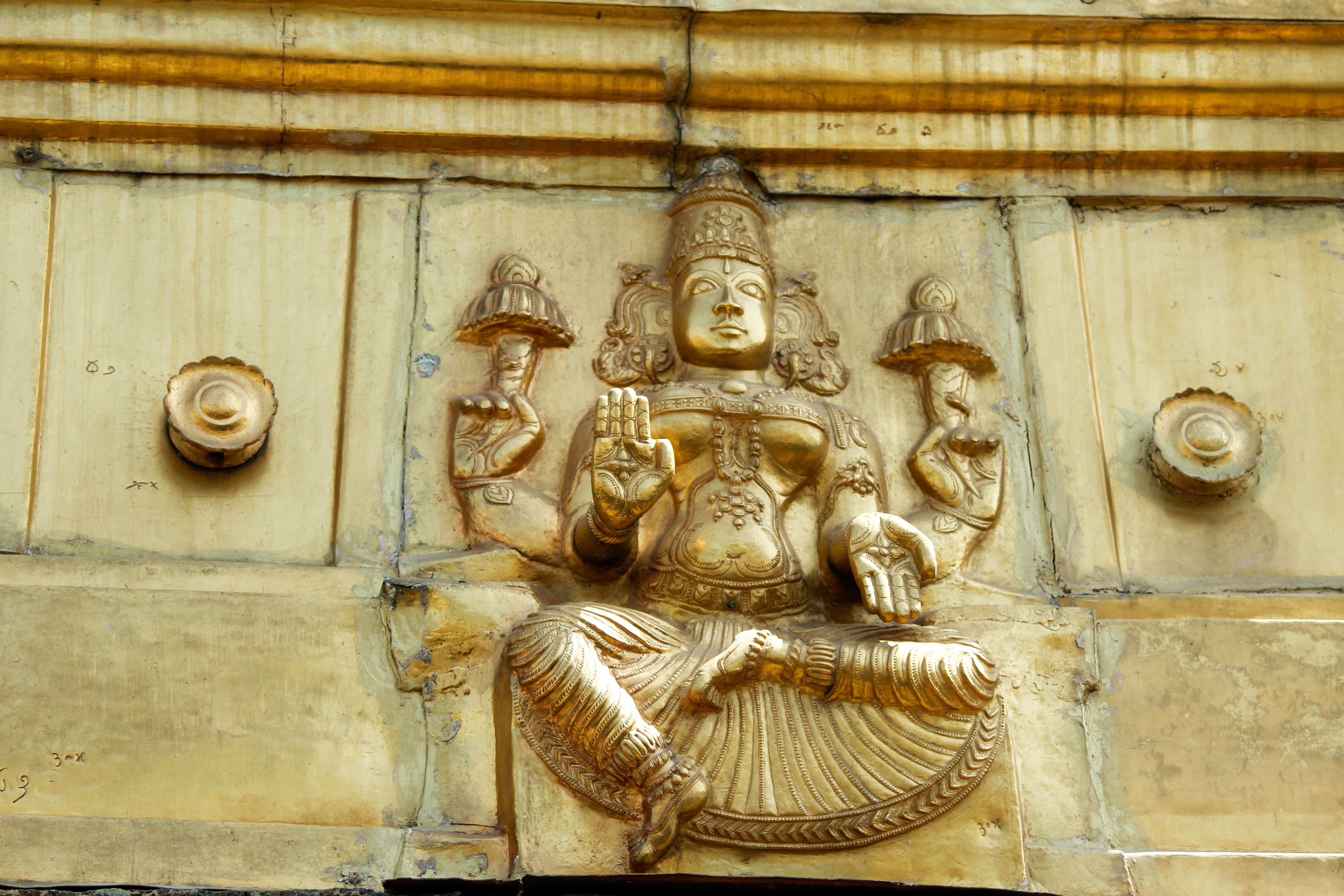 Golden carving depicting a deity from Hindu mythology on a temple wall.