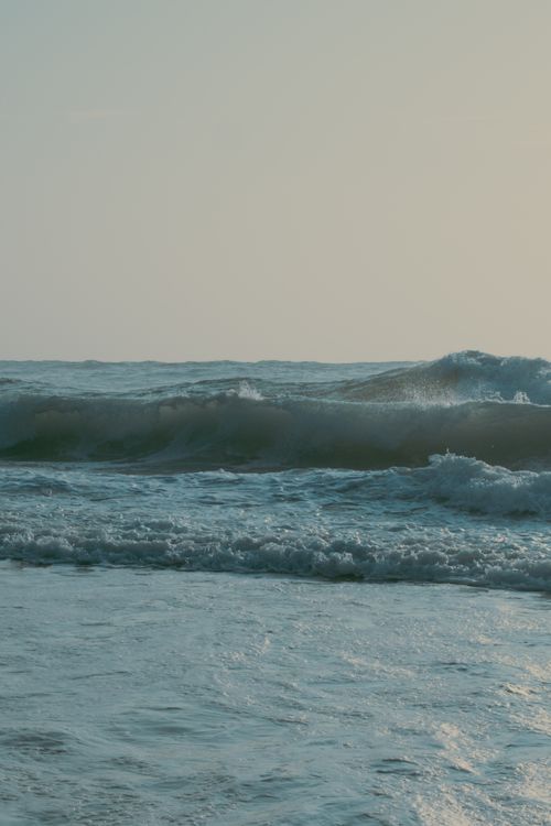 Free Calm ocean waves rolling gently under a soft sunset light, evoking a tranquil and serene mood. Stock Photo