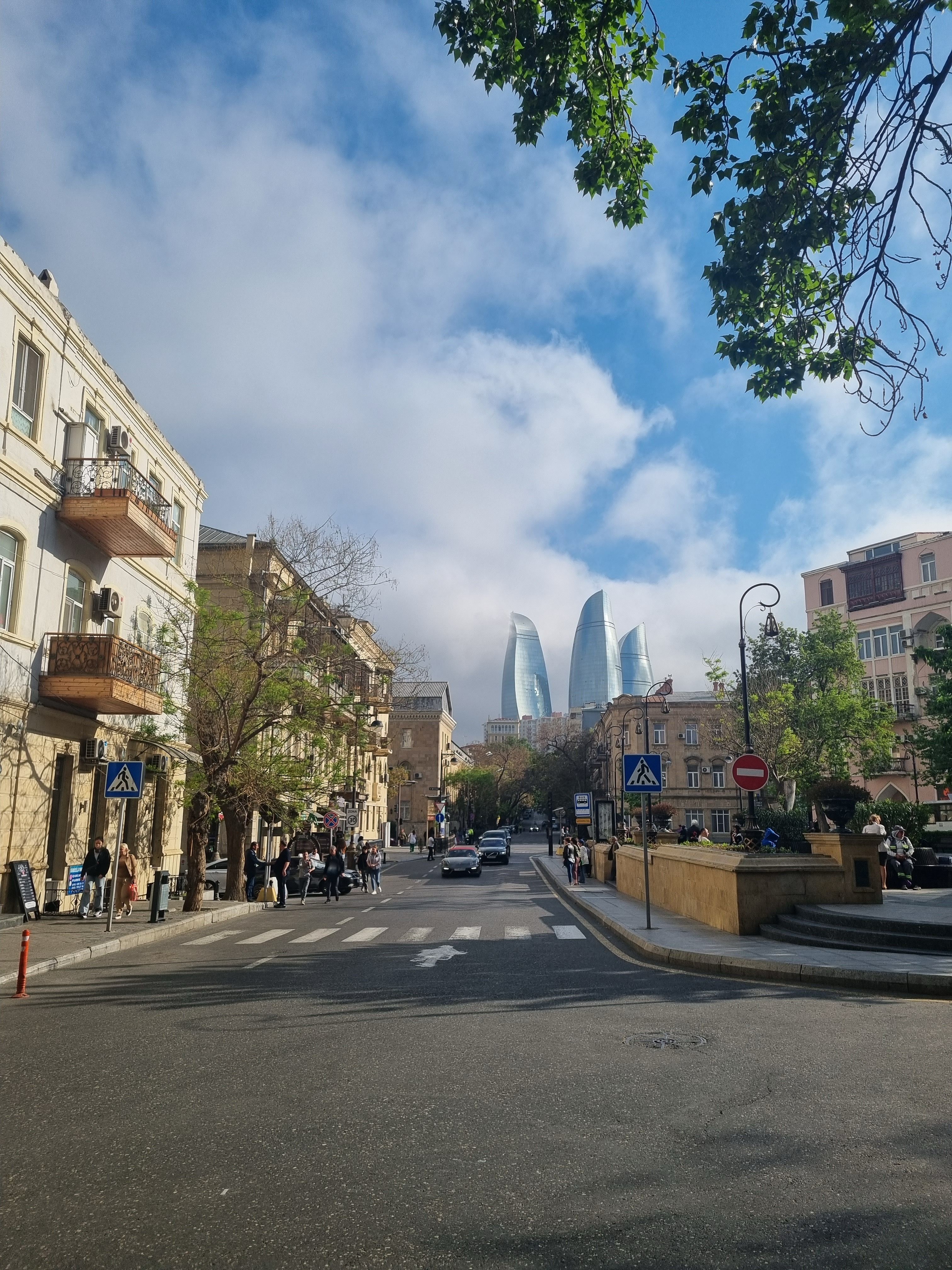 Street scene in Baku with a view of the iconic Flame Towers under a blue sky.
