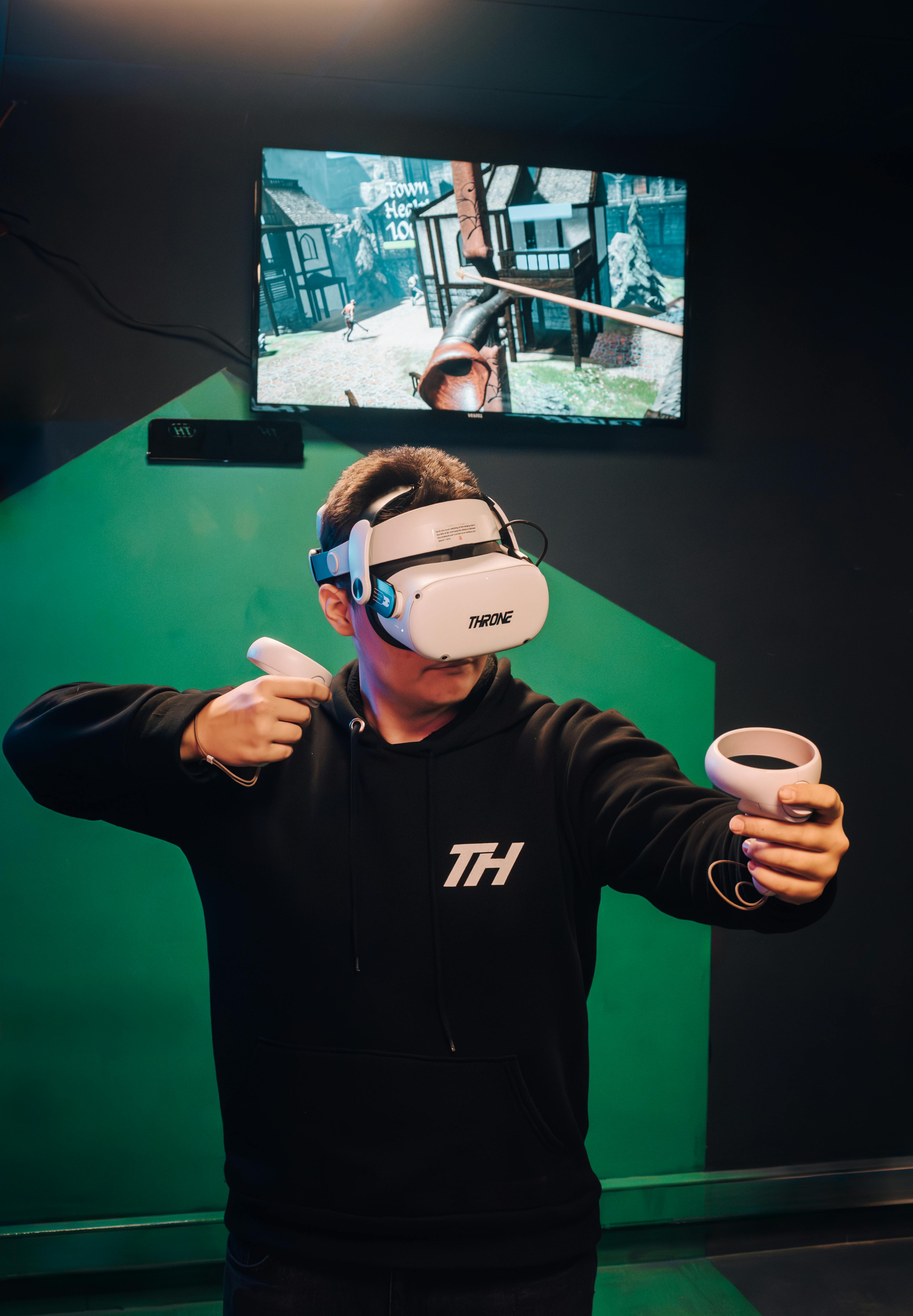 Person immersed in virtual reality gaming with VR headset and controllers indoors.