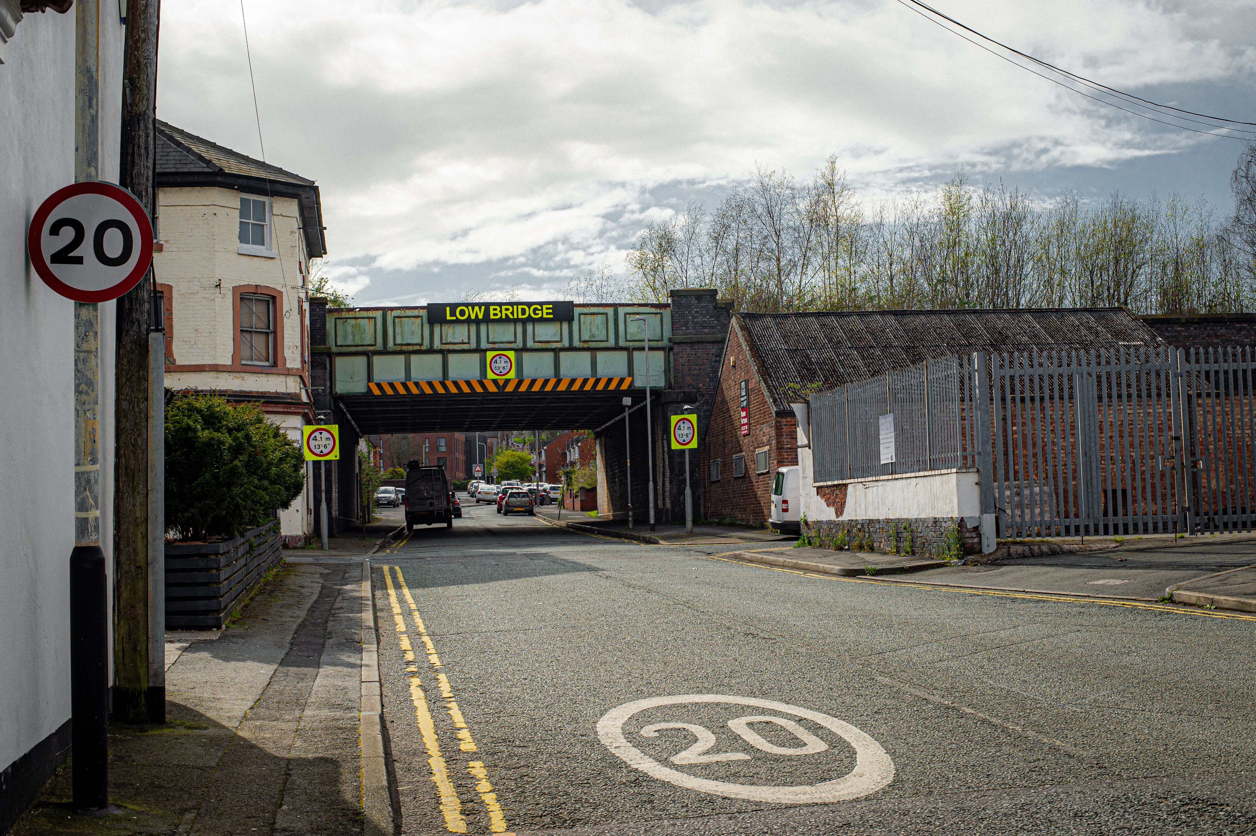 Street view in Liverpool featuring a low bridge and various traffic signs including speed limit indicators.