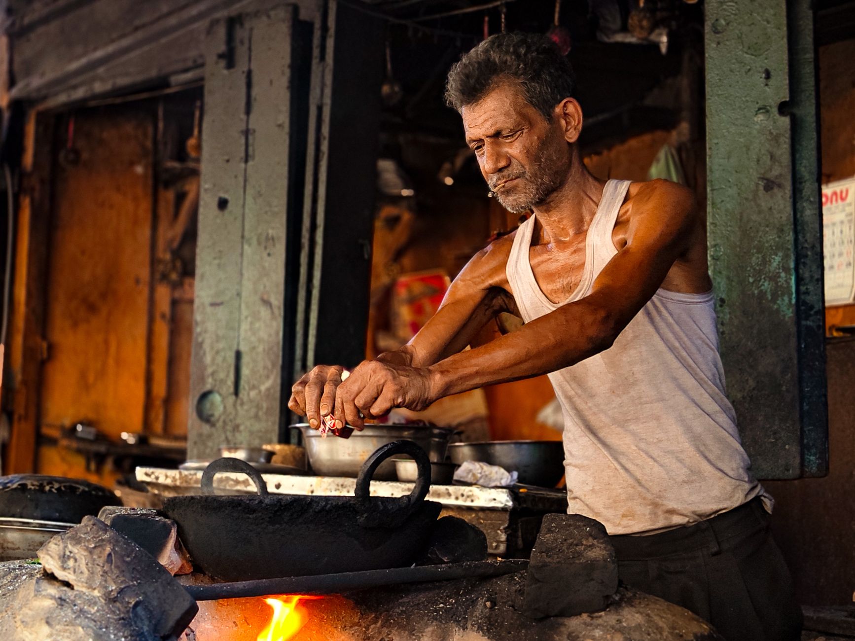 Cook frying stuffed parathas in a wide iron pan in a narrow Old Delhi lane