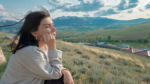 Free Contemplative woman sitting outdoors with scenic mountain views, serene and peaceful. Stock Photo