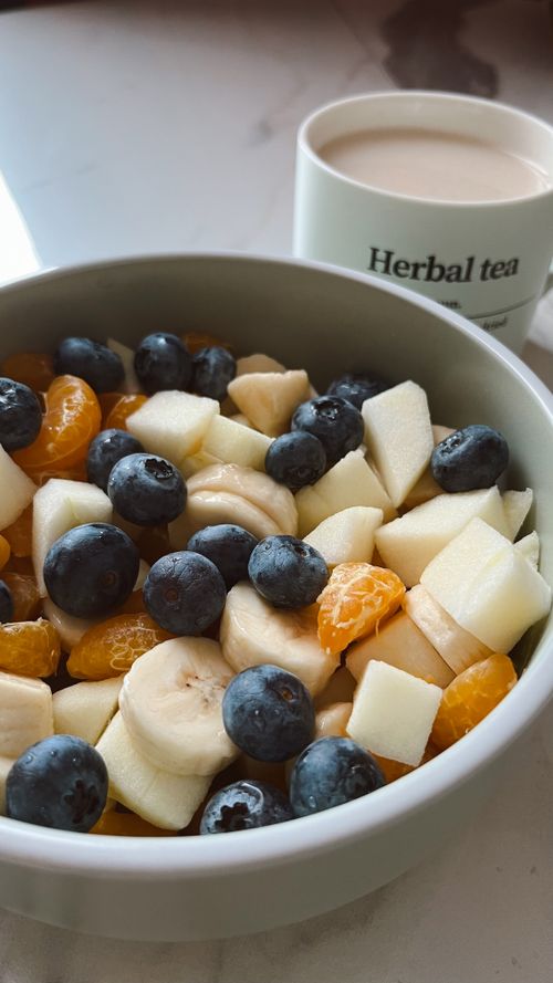 Free A vibrant bowl of fresh fruit salad paired with a cup of herbal tea on a tabletop. Stock Photo