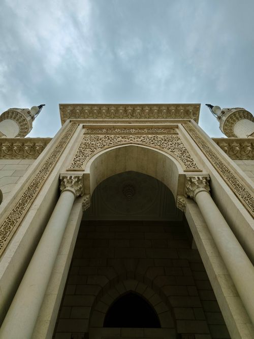 Free An intricate archway with detailed carvings viewed from below with a cloudy sky backdrop. Stock Photo